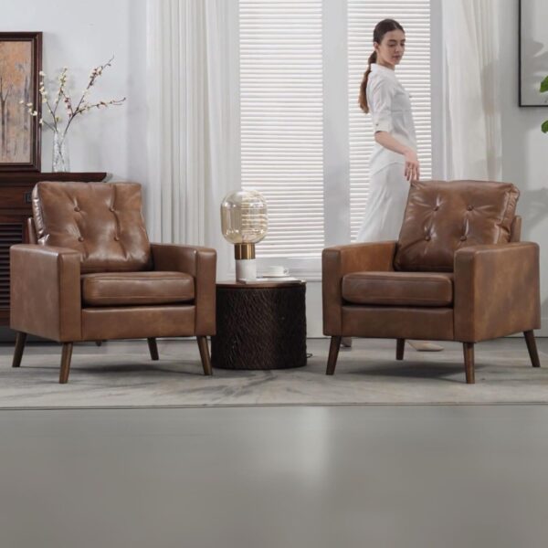 Two caramel leather chairs in a room, with a woman standing in front, showcasing a modern accent chair design.
