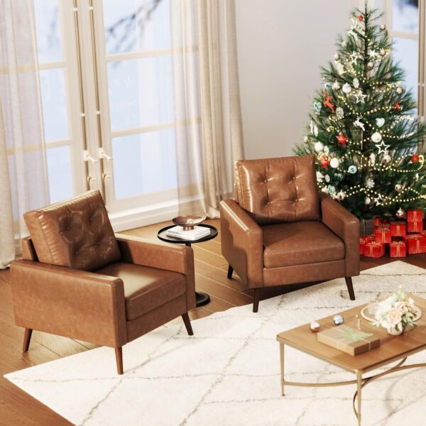 A cozy living room featuring two caramel-colored leather chairs and a beautifully decorated Christmas tree.