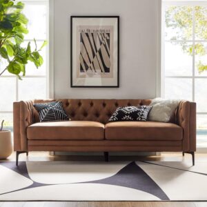 A Camel leather couch with metal legs, button-tufted design, positioned in front of a window in a modern living room.
