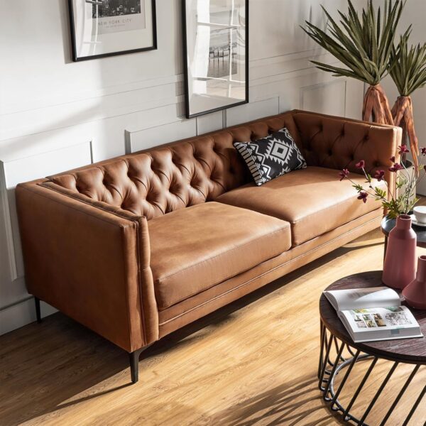 A Camel faux leather couch with metal legs, featuring button-tufting, in a stylish living room setting.
