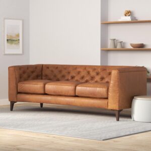 A tan leather couch in a living room, featuring tufted back and feather-down topper, made of vintage pure-aniline Italian leather.
